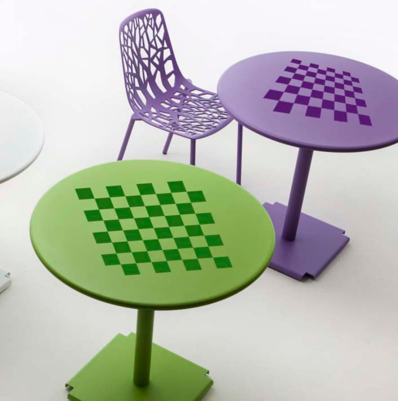 May include: Two round tables with a checkerboard pattern on top. One table is green with a green checkerboard and the other is purple with a purple checkerboard. A purple chair with a unique design is in the background.