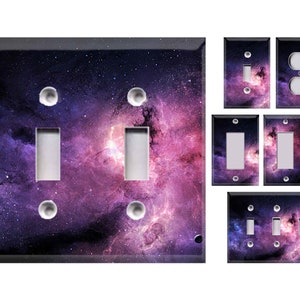 May include: A collection of light switch covers featuring a vibrant galaxy design in shades of purple, pink, and blue. The set includes various configurations, such as single, double, and triple switch plates, and a double outlet cover. The covers have a glossy finish.