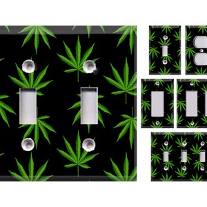May include: A set of light switch and outlet covers featuring a black background with a repeating pattern of green marijuana leaves.