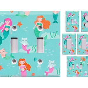 May include: A set of light blue, teal, pink, orange, and white light switch covers with a mermaid and cat pattern. The pattern includes mermaids with long hair, tails, and seashells, as well as cats with mermaid tails. The background is a light blue with white fish and starfish.