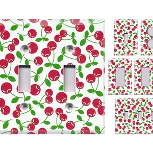 May include: A set of light switch covers featuring a red cherry pattern on a white background. The set includes a single switch cover, a double switch cover, and a triple switch cover.