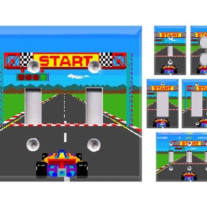 May include: A light blue and black light switch cover with a pixelated image of a race car game. The image shows a race car crossing the finish line with the word "START" above it.
