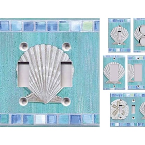 May include: A set of light blue and white seashell themed light switch covers. The covers feature a seashell design with a mosaic border.