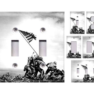 May include: A set of light switch covers featuring a black and white photograph of soldiers raising the American flag on Iwo Jima. The image is a classic representation of American patriotism and military service.