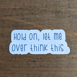 May include: White sticker with blue text that reads "Hold on, let me overthink this".