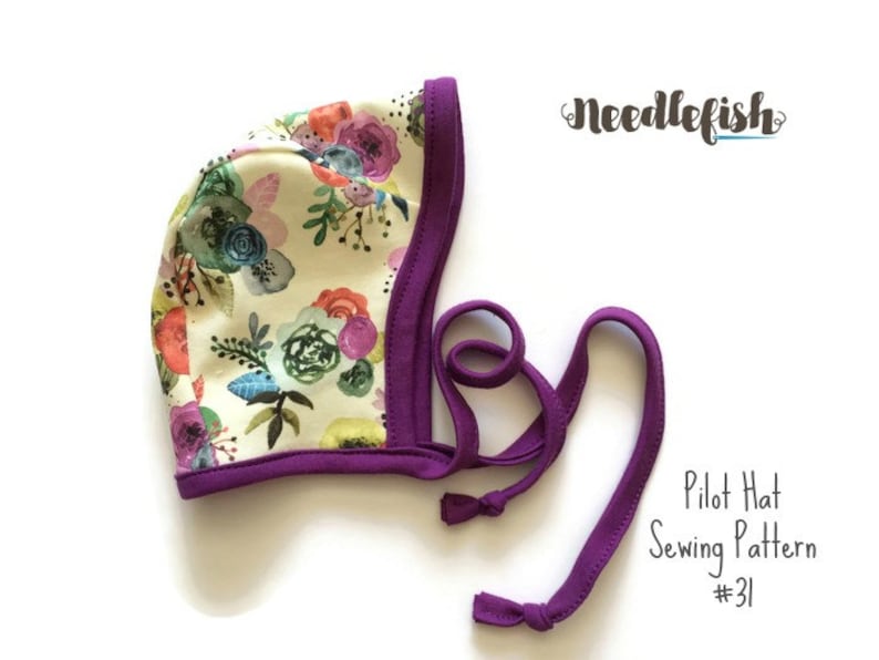 May include: A purple and white floral pilot hat sewing pattern. The pattern is called "Pilot Hat Sewing Pattern #31" and is from the company "Needlefish".