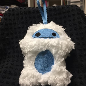Puede incluir: Adorno de yeti blanco de felpa con cara, vientre y lazo para colgar azules. El yeti tiene ojos negros y una boca peque&ntilde;a. El adorno est&aacute; hecho de material suave y esponjoso y est&aacute; dise&ntilde;ado para colgar.