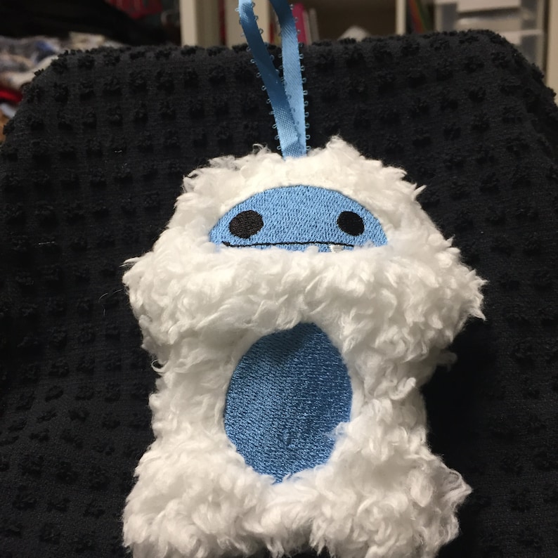 Puede incluir: Adorno de yeti blanco de felpa con cara, vientre y lazo para colgar azules. El yeti tiene ojos negros y una boca peque&ntilde;a. El adorno est&aacute; hecho de material suave y esponjoso y est&aacute; dise&ntilde;ado para colgar.