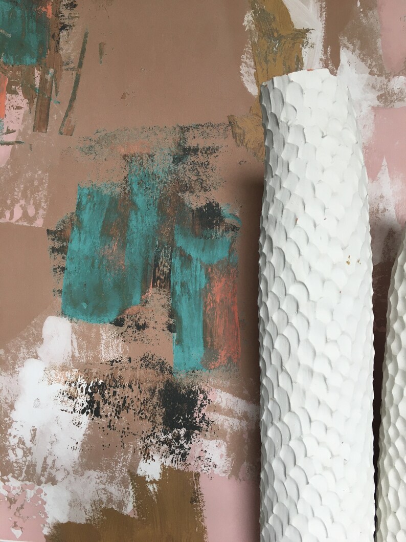May include: Two white ceramic vases with a textured, scale-like pattern. The vases are against a background of abstract brushstrokes in shades of pink, brown, teal, and gold.