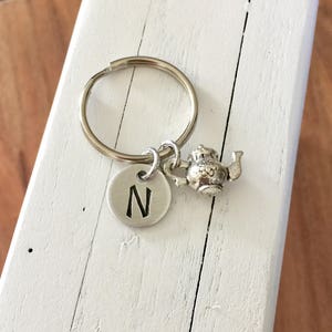 May include: Silver keychain with a teapot charm and a round charm with the letter N engraved on it.