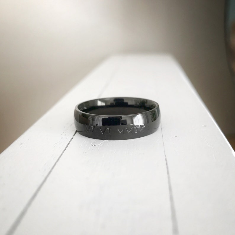 K&ouml;nnte beinhalten: Ein schwarzer Ring mit einer r&ouml;mischen Zifferninschrift "VI.VII.MMIX", die in die Band graviert ist.