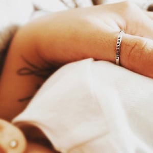 May include: A silver ring with the inscription "1983-2018" on a person's finger.