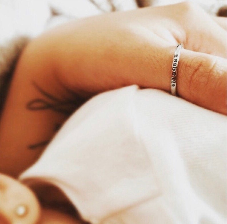 May include: A silver ring with the inscription "1983-2018" on a person's finger.