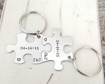 May include: Silver puzzle piece keychains with the date 04-14-15 and the initials J&J engraved on them. The keychains are connected together.