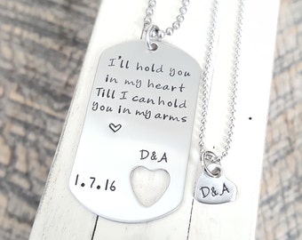 May include: Two silver necklaces with matching heart pendants. The larger pendant has a cutout heart and the inscription "I'll hold you in my heart Till I can hold you in my arms" with the date "1.7.16" and the initials "D&A". The smaller pendant has the initials "D&A".