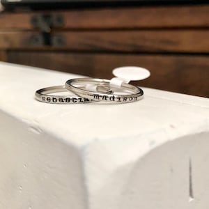 May include: Two silver rings with the names "Sebastian" and "Madison" engraved on them.