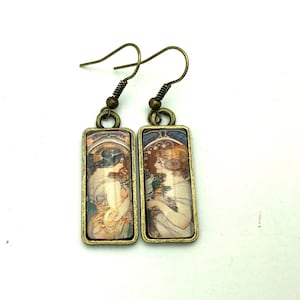 Peut inclure: Une paire de boucles d'oreilles en bronze avec des panneaux de verre rectangulaires représentant une impression art nouveau vintage de deux femmes dans un décor floral.
