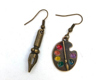 Boucles d’oreilles dépareillées, palette d’artiste et une breloque plume Sergent-major, laiton.