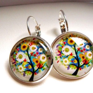 May include: Silver dangle earrings with a round glass charm featuring a colourful tree with flowers and birds.