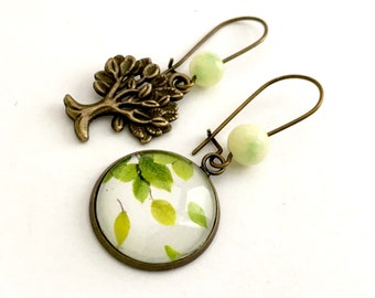 Mismatched dangling tree earrings and leaves flying in the wind. Green beads.