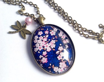 Collier sautoir cabochon ovale fleurs de cerisier sur fond bleu, libellule et perle rose, en bronze.