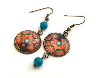 Asymmetrical flower earrings in orange, turquoise and brown tones, dangling in bronze.