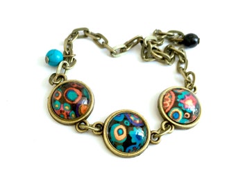 Pulsera con flores y círculos multicolores sobre fondo negro, cabujones de cristal, perlas.