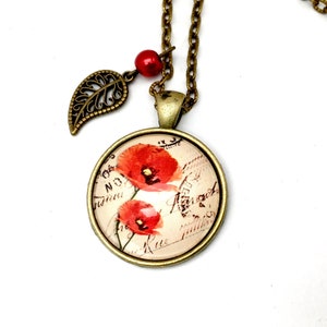 May include: A bronze necklace with a round pendant featuring a vintage postcard image of red poppies. The pendant is attached to a bronze chain with a small bronze leaf charm and a red bead.