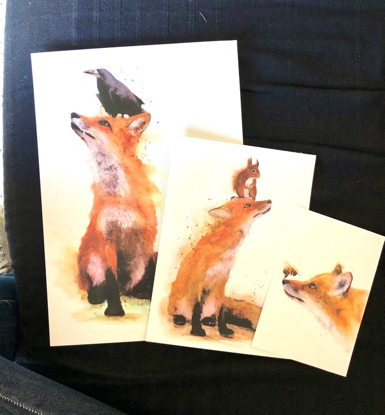 May include: Three watercolour paintings of foxes. The first painting features a fox with a black crow perched on its head. The second painting features a fox with a squirrel perched on its head. The third painting features a fox looking at a bee.