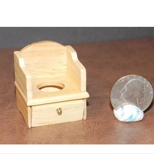 May include: A miniature wooden potty chair with a drawer and a gold knob. The chair is about the size of a quarter.