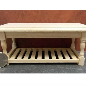 Peut inclure: Une petite table basse en bois avec une étagère inférieure. La table a une finition en bois clair et naturel et des pieds tournés. La table mesure environ 7.6 cm de long, 5 cm de large et 5 cm de haut.