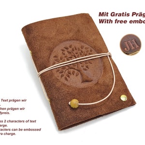 Könnte beinhalten: Braunes Lederjournal mit einem geprägten Baumdesign auf dem vorderen Umschlag. Das Journal hat einen beigefarbenen Lederriemen und eine goldene Perle. Der Text "Mit Gratis Prägung With free embossing" ist oben im Bild gedruckt. Der Text "JH" ist auf einen braunen Lederkreis geprägt.