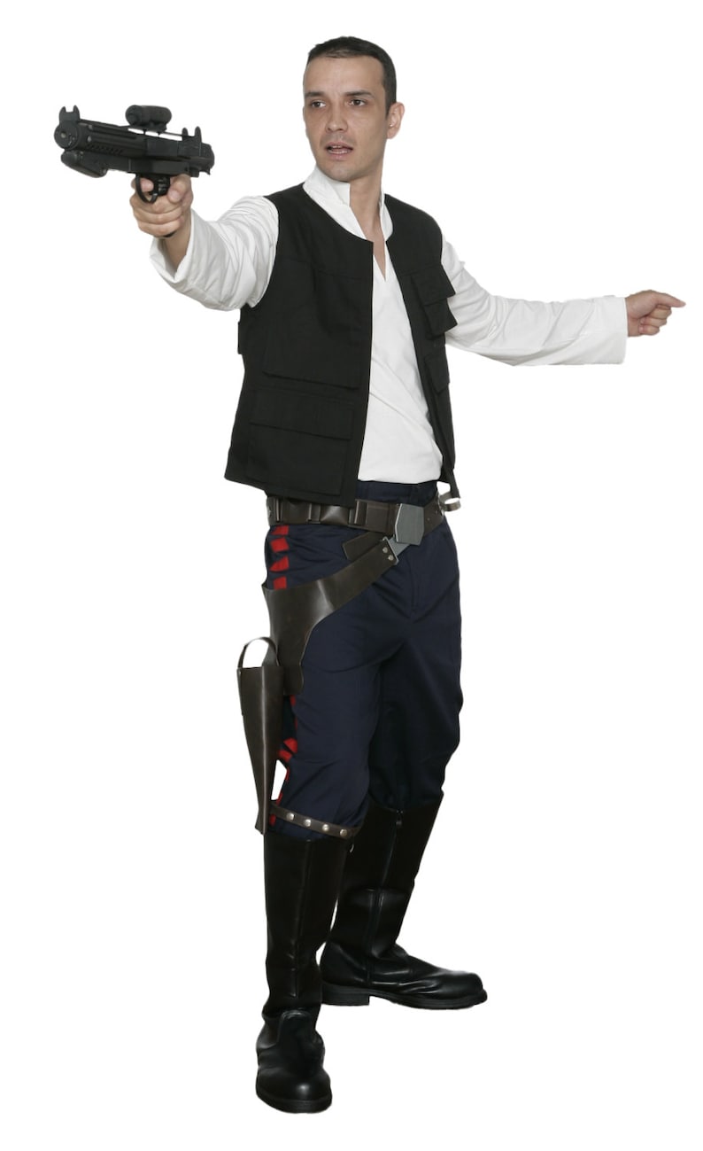 May include: A costume featuring a black vest, white shirt, and dark blue pants. The outfit includes a holster, belt, and black boots. A prop blaster is held in the right hand, with the person pointing with the left hand.