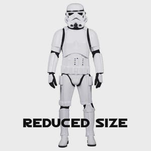 May include: A full-body image of a white Stormtrooper action figure from Star Wars. The figure is wearing a white helmet, armor, and boots, with black accents. The text "REDUCED SIZE" is displayed in black at the bottom of the image.