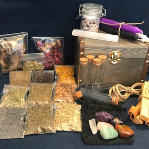 May include: A wooden box with a latch and a variety of herbs, spices, and crystals. The box is filled with small bags of dried herbs and spices, as well as a few glass vials and a small bag of crystals. The box is also decorated with a few pieces of cinnamon sticks and a small piece of twine.