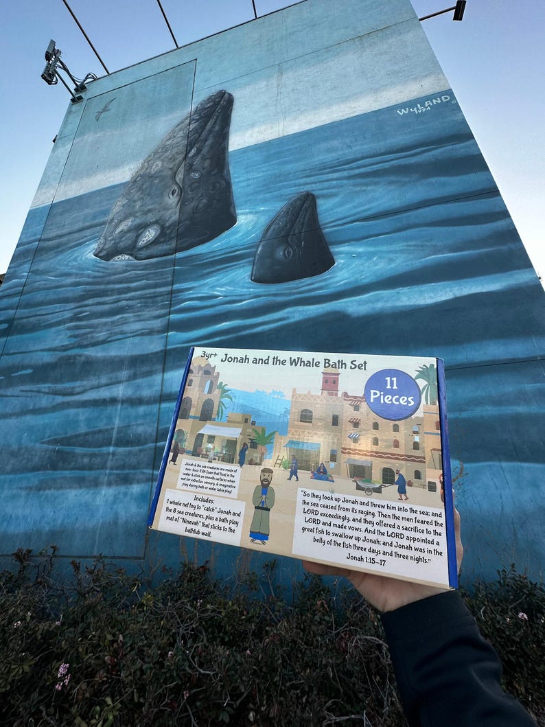 May include: A colorful box for a bath toy set featuring Jonah and the Whale. The box has a picture of a city with a blue sky and a whale in the water. The text on the box reads "3yrt Jonah and the Whale Bath Set 11 Pieces". The text on the back of the box reads "So they took up Jonah and threw him into the sea, and the sea ceased from its raging. Then the men feared the LORD exceedingly, and they offered a sacrifice to the LORD and made vows. And the LORD appointed a great fish to swallow up Jonah, and Jonah was in the belly of the fish three days and three nights. Jonah 1:15-17"
