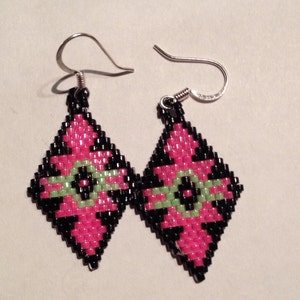 Op de afbeelding: Een paar diamantvormige oorbellen met zwart, roze en groen kralenwerk.
