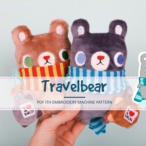 May include: Two plush brown and gray bears wearing striped scarves. The bears are holding small bags with the text "I love Berlin". The text "Travelbear PDF 1TH EMBROIDERY MACHINE PATTERN" is below the bears.