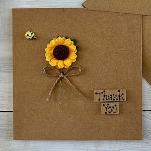 May include: A brown card with a sunflower and a bee on it. The card says "Thank You".