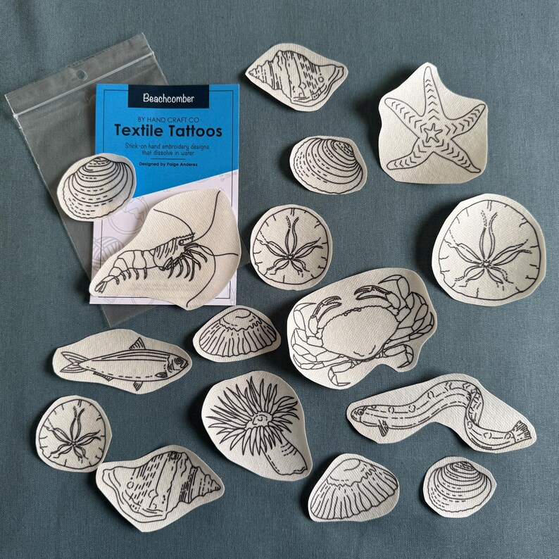 Pode incluir: Uma cole&ccedil;&atilde;o de tatuagens t&ecirc;xteis com v&aacute;rias criaturas marinhas e conchas, incluindo uma estrela do mar, um caranguejo e camar&otilde;es. As tatuagens s&atilde;o em arte de linha preta sobre tecido bege. Um pacote de "Beachcomber Textile Tattoos" tamb&eacute;m est&aacute; inclu&iacute;do.