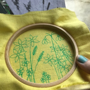 Start by transferring your desired flowers to the fabric by holding it tight in a hoop in front of a sunny window.