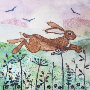 May include: A brown hare leaps through a field of green grass and wildflowers under a full moon. The sky is a soft pink and purple.