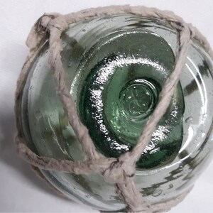May include: A green glass fishing float with a white rope tied around it.