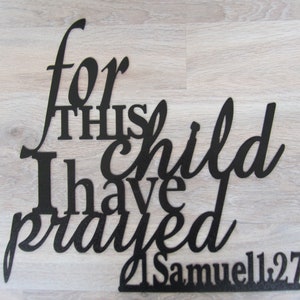 May include: Black metal wall art with the words "for this child I have prayed" and the scripture reference "1 Samuel 1:27".