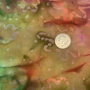 May include: A close-up of a brown fabric with a tie-dye pattern in shades of green, pink, and orange. A silver US quarter is placed on the fabric.