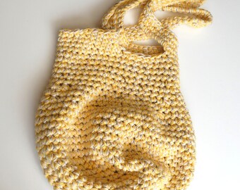May include: A yellow and white crocheted tote bag with a knotted handle. The bag is made with a simple stitch pattern and has a relaxed, casual look.