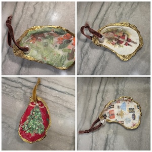 May include: Four oyster shell ornaments with gold-painted edges and velvet ribbons. Designs include a Santa Claus figure, a Christmas tree on a red background, a winter botanical scene with berries, and a pattern of nutcrackers and holiday gifts.