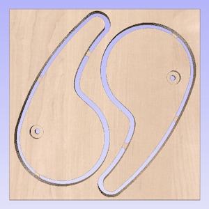 May include: Two wooden cutouts in the shape of a yin yang symbol. The cutouts are on a light brown wooden surface.