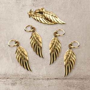 May include: Five gold angel wing charms with a loop for attaching to jewelry. The charms are about 1 inch long and have a detailed design.