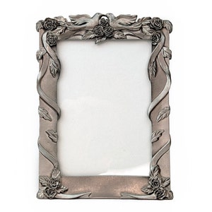 May include: A silver-toned picture frame with a decorative design of doves, roses, and vines. The frame is rectangular and has a smooth, polished finish.